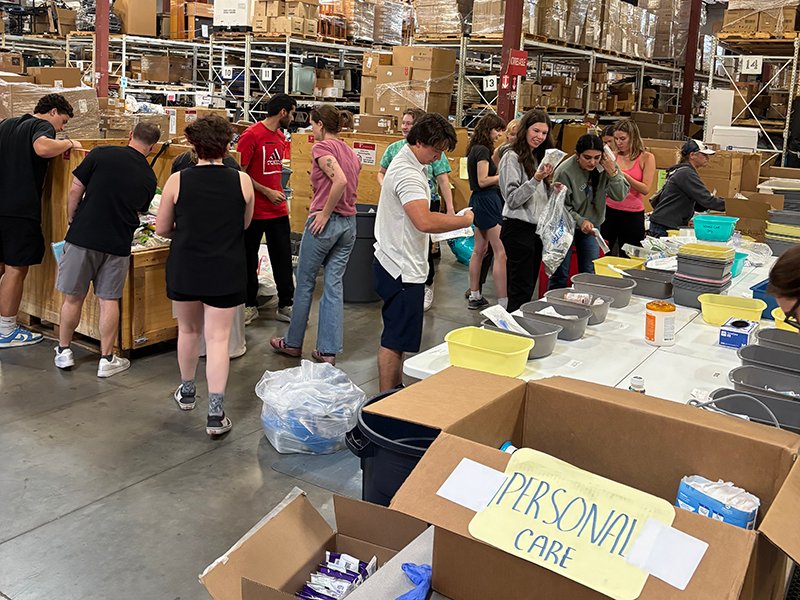 students sort items in a warehouse as part of a Day of Service project