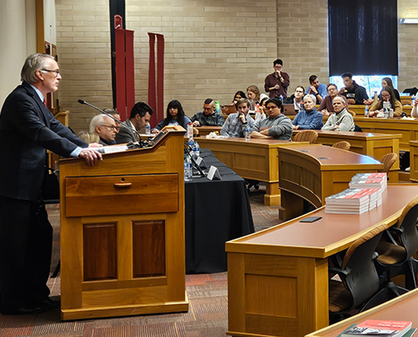 speaker at podium addresses audience in classroom