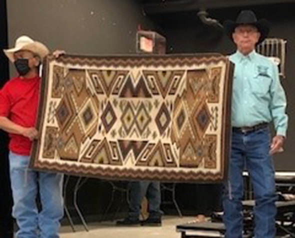 Tribal members displaying hand-sewn rug
