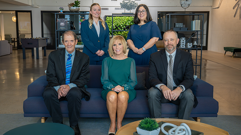 Individuals seated on couch and standing behind it