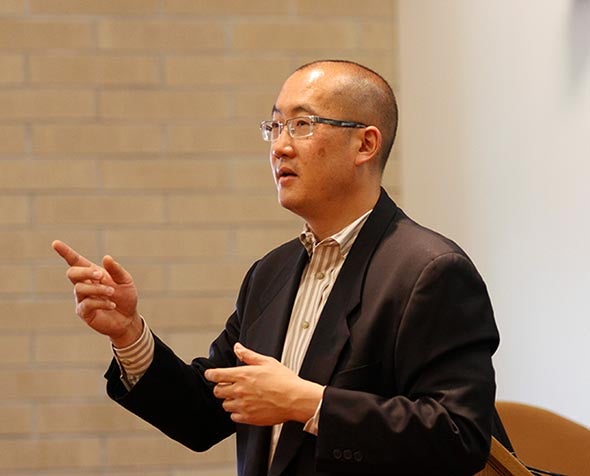 Bernard Chao with arms extended, speaking