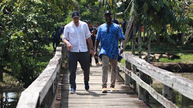 two men walking across wooden bridge over a river