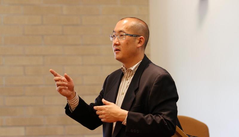 Bernard Chao with arms extended, speaking