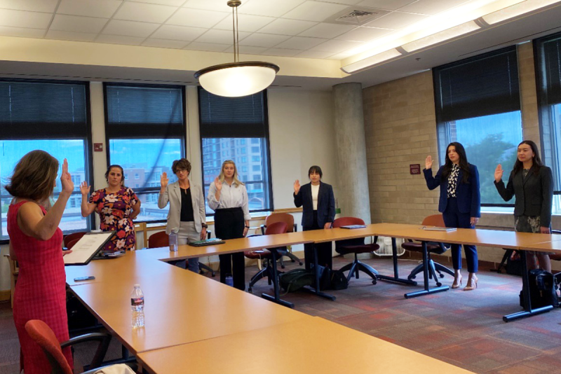 students raise their right hands to take oath in classroom