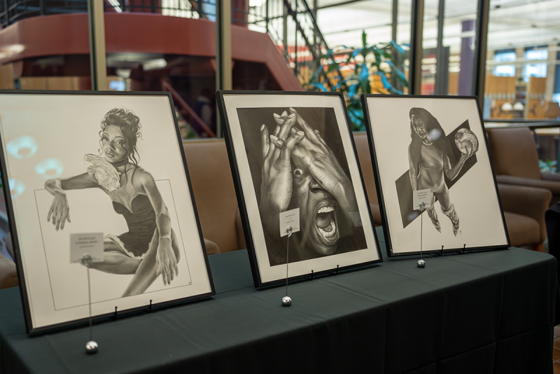 Three framed black and white drawings displayed on table