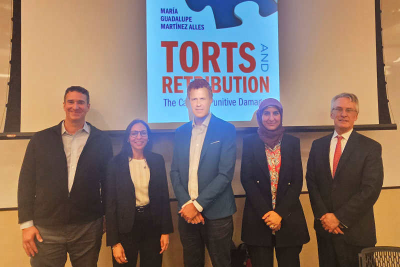 Group photo of five individuals in front of screen displaying book title