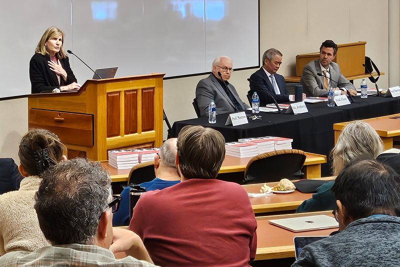 speaker at podium and panelists